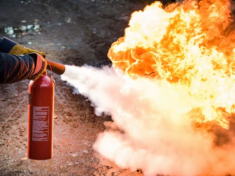 Participants s'entraînant à la manipulation des extincteurs sur feu réel simulé